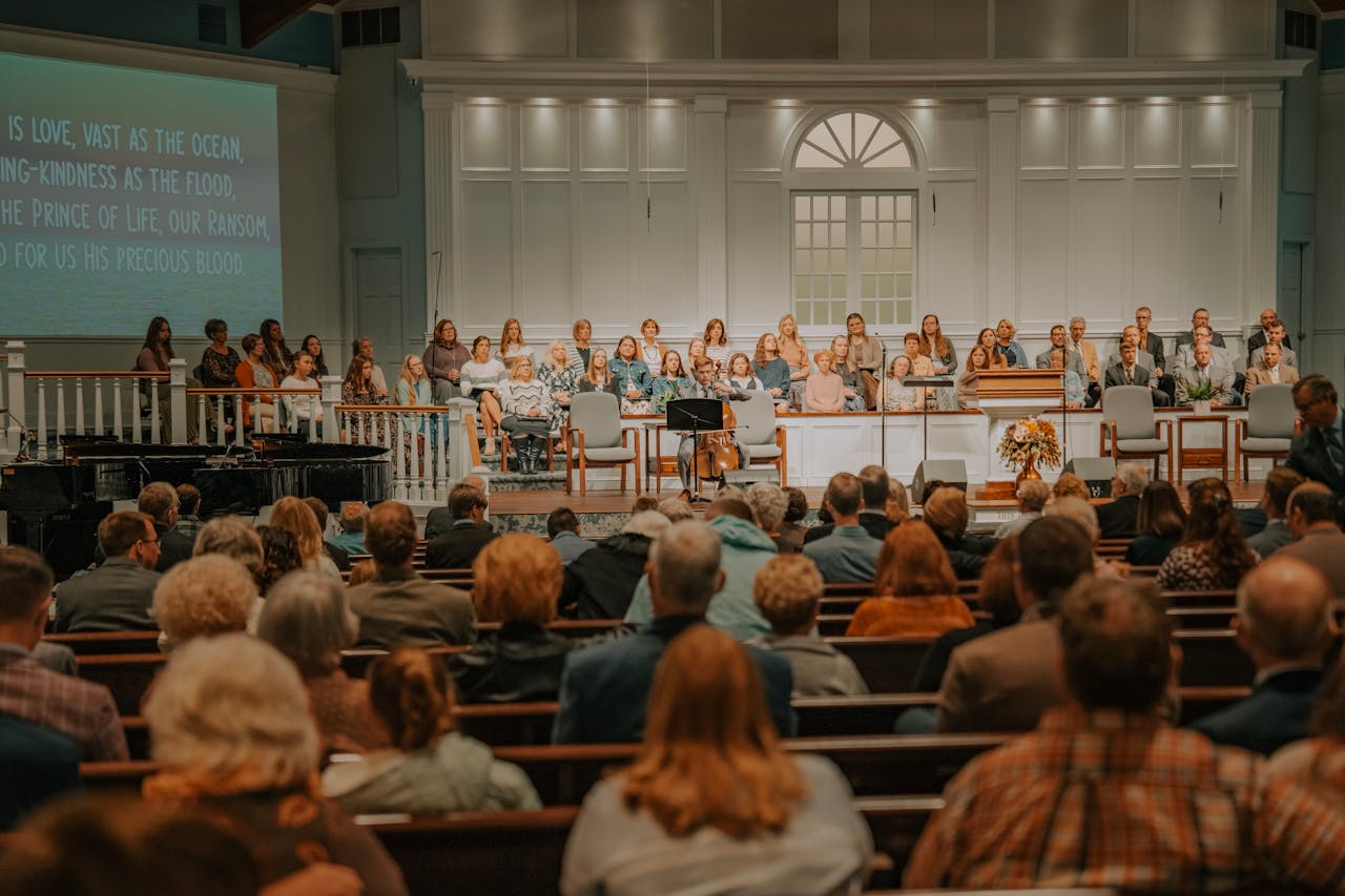 A large congregation seated in a church auditorium during a service with choir and musical instruments.
